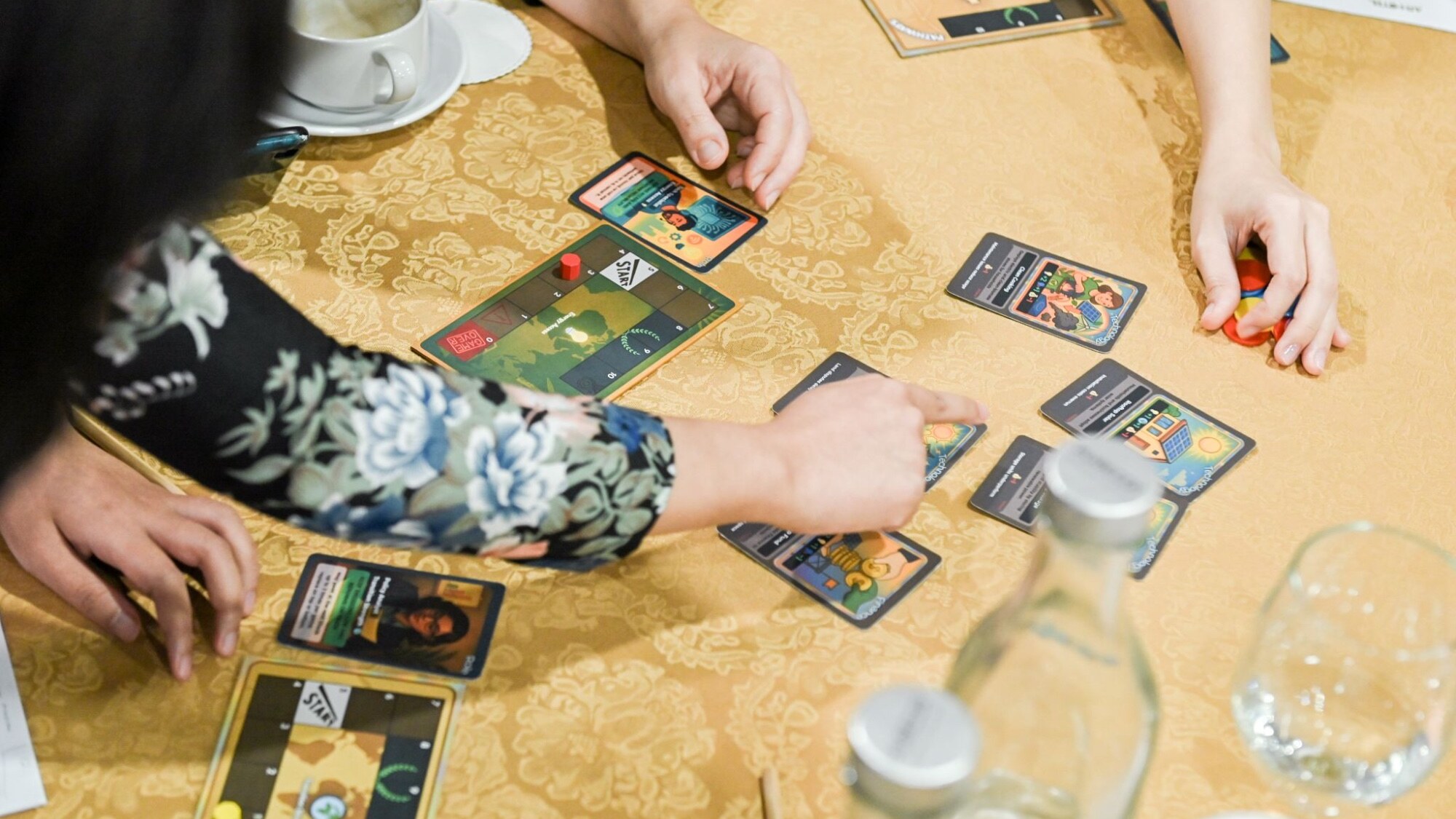 Close-up of the Energy Transition Game being played, showing action cards, tokens, and participants making resource allocation decisions